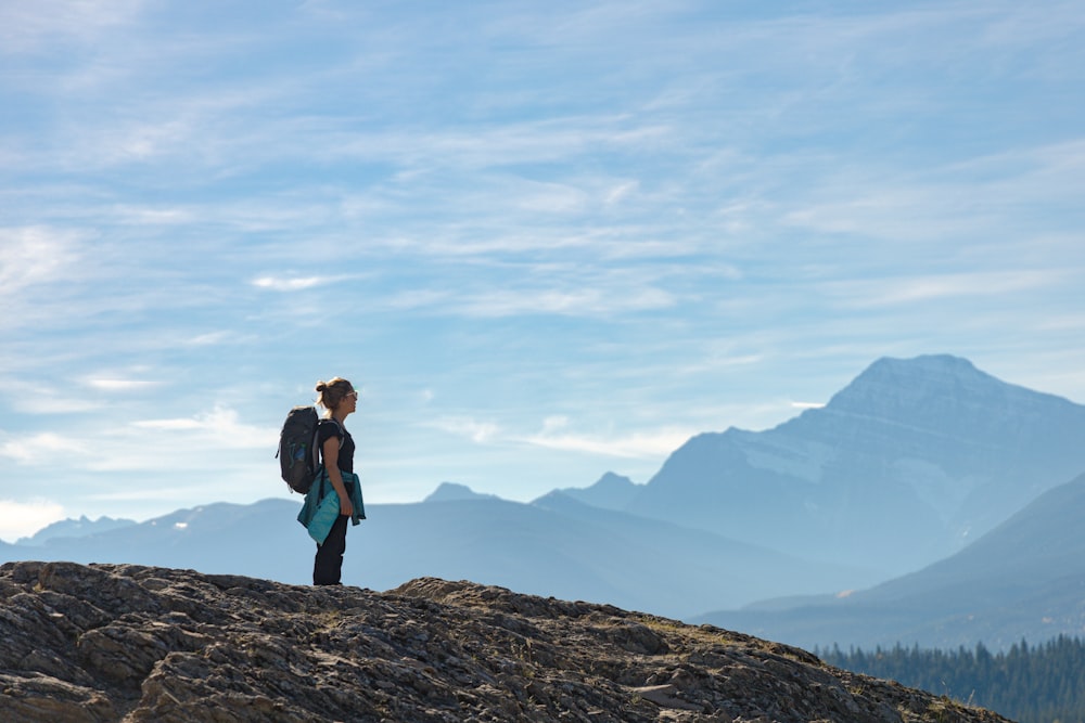 a woman standing on top of a mountain with a backpack