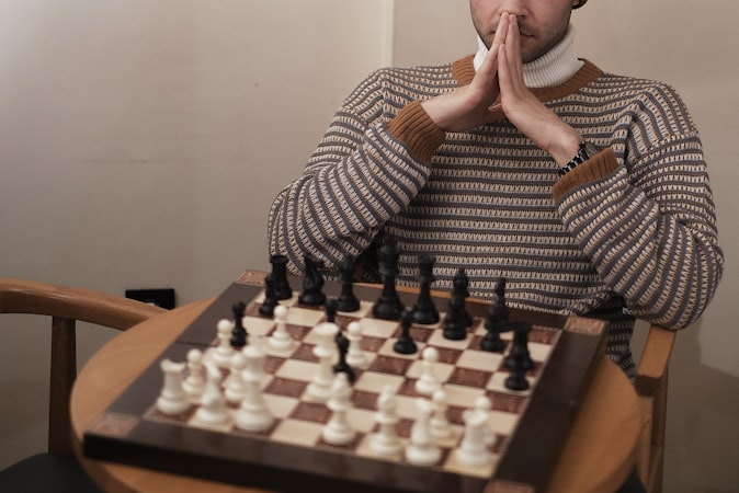 A chess player deep in thought at a tournament board in moody lighting