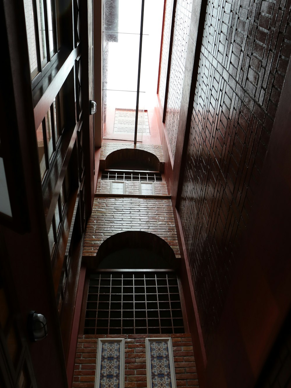 a narrow hallway with a brick wall and two windows