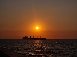 A sleek cargo ship sailing smoothly on the ocean at sunrise, symbolizing efficient fuel use.