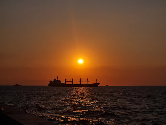 A dynamic cargo ship sailing under a vibrant sunset, symbolizing global freight movement.