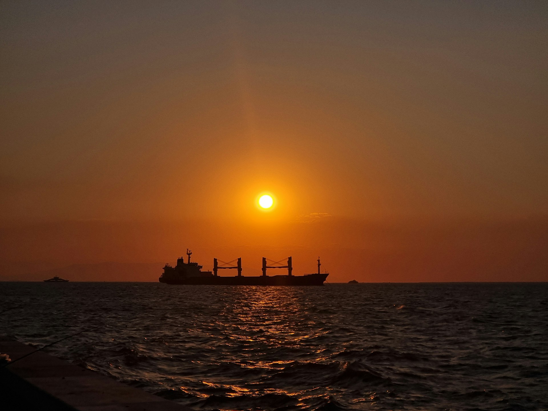 A dynamic cargo ship sailing at sunset, symbolizing global maritime shipping and trade.