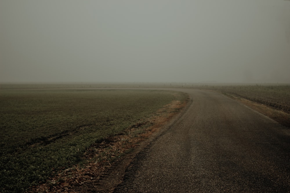 a foggy road in the middle of a field