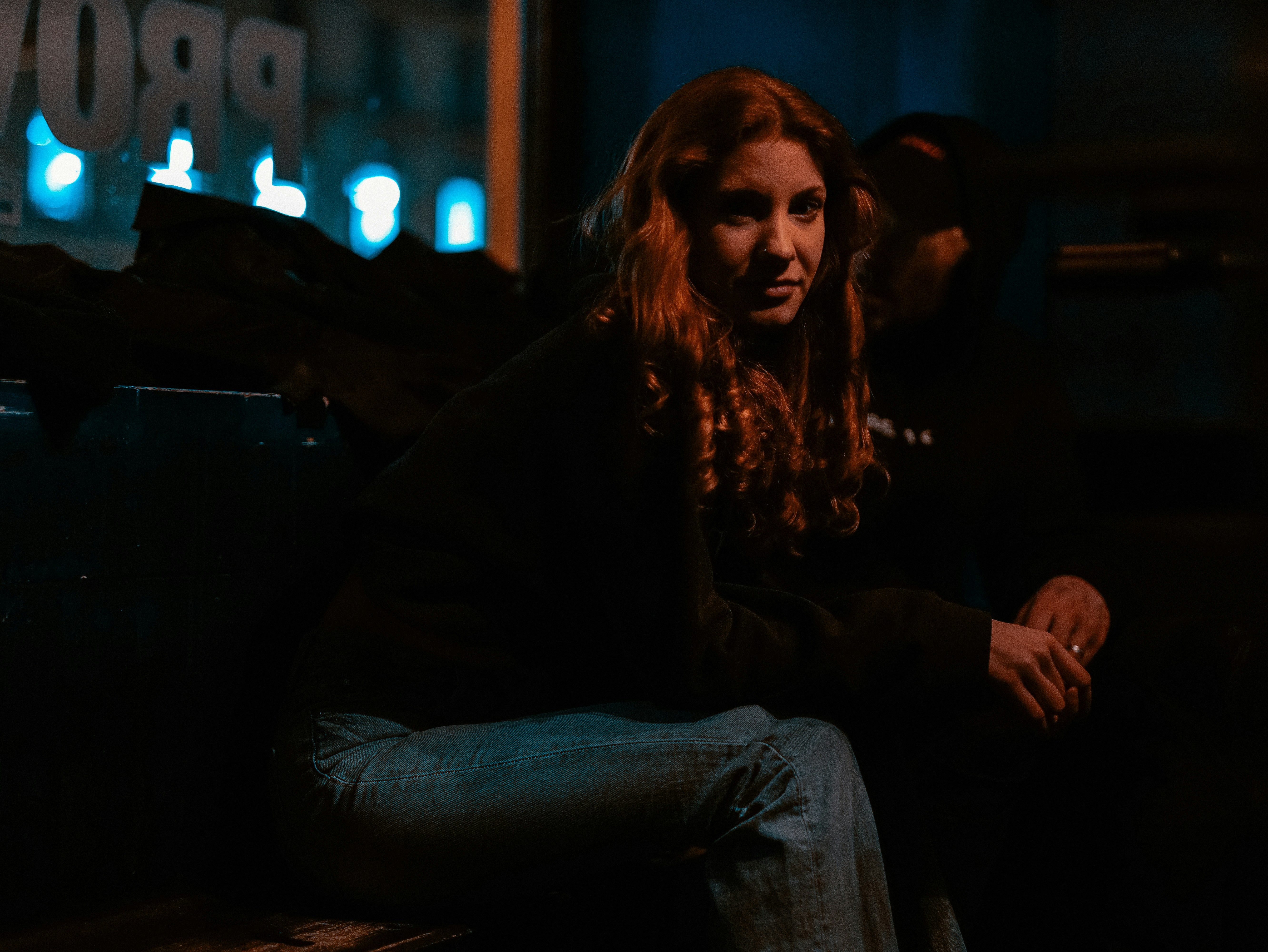 a woman sitting on a bench in the dark