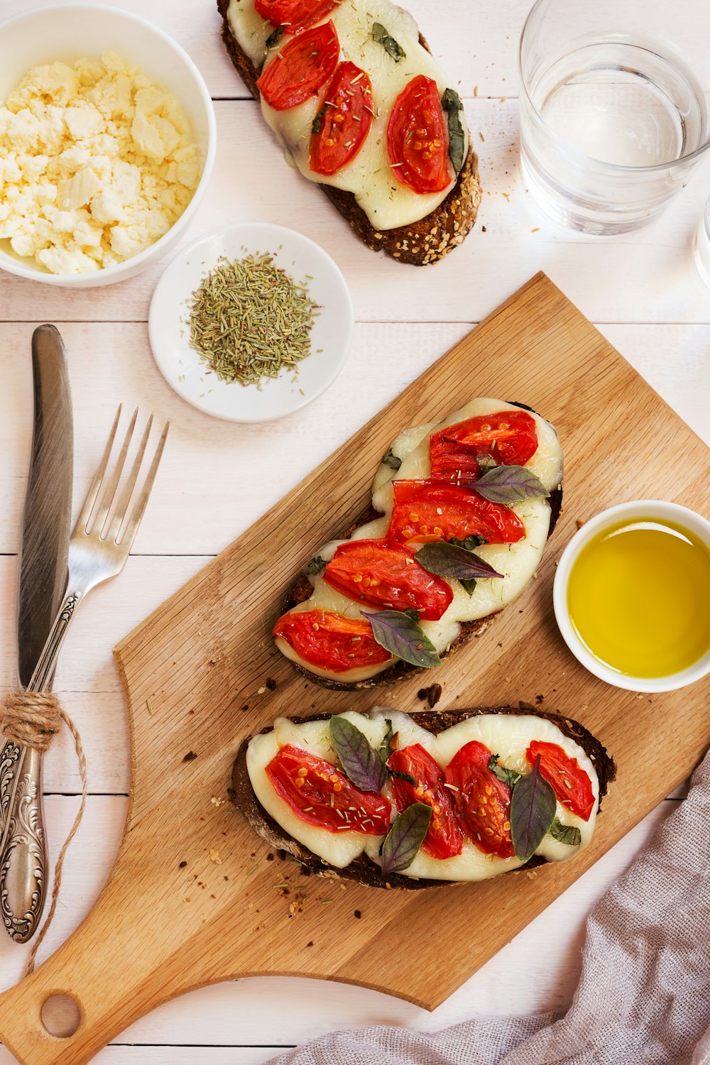 a wooden cutting board topped with slices of bread covered in toppings