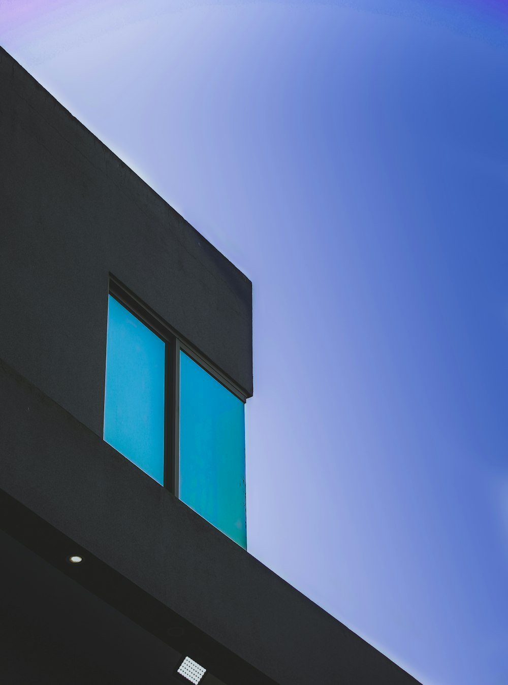 a building with two windows and a blue sky in the background