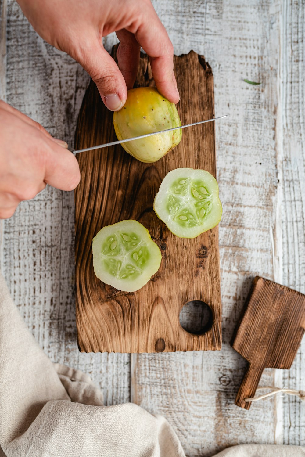 a person cutting up a cucumber on a cutting board