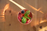 a glass of fruit and mint on a wooden table