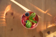 a glass of fruit and mint on a wooden table