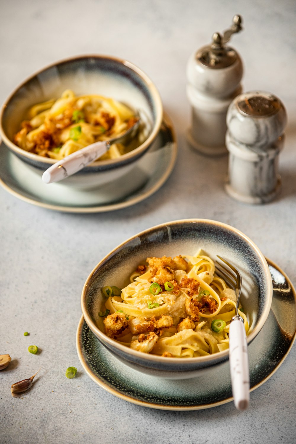 two bowls of food on a table with a spoon