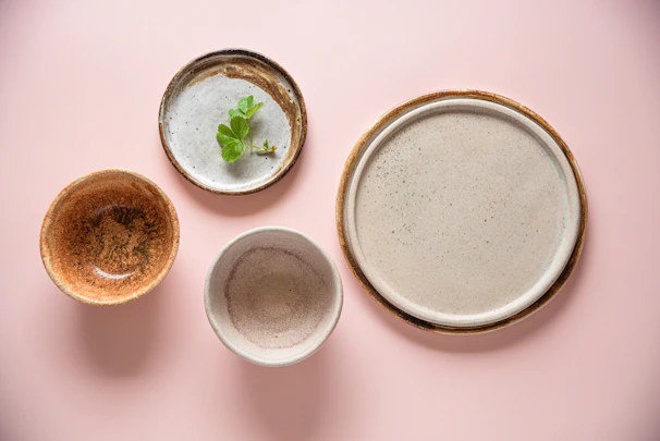 A set of handmade plates in soft pastel shades arranged on a rustic linen cloth.