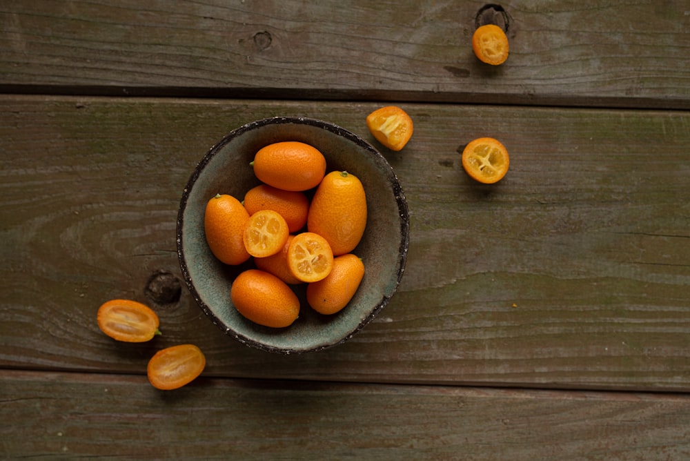 a bowl filled with oranges on top of a wooden table