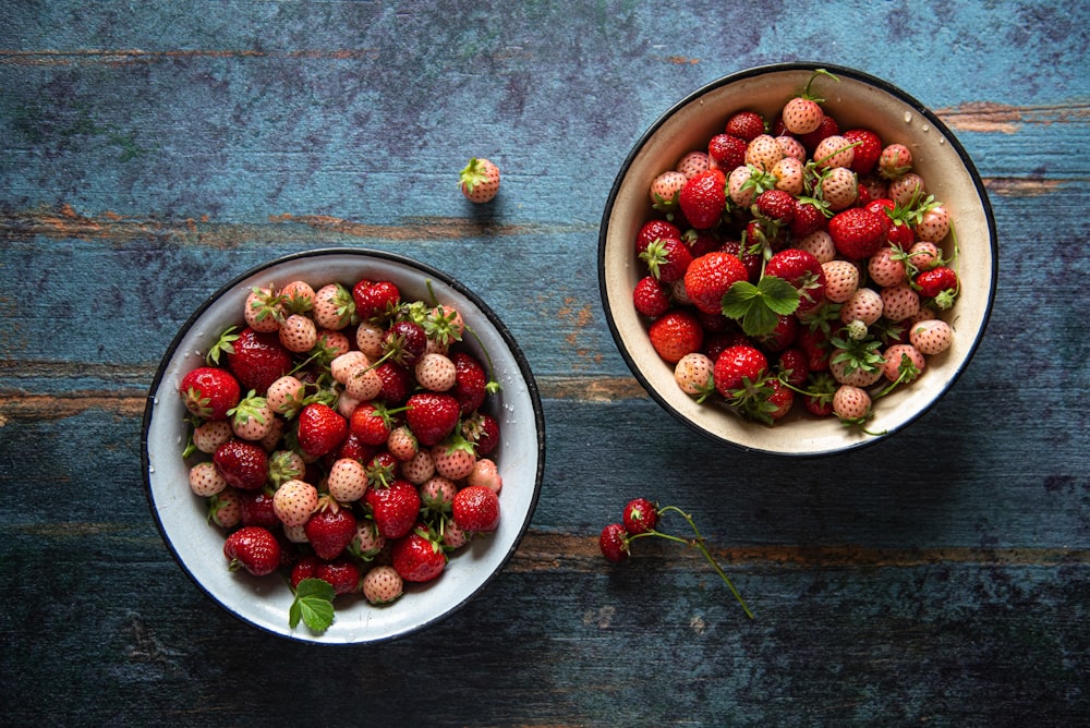 two bowls of strawberries on a wooden table