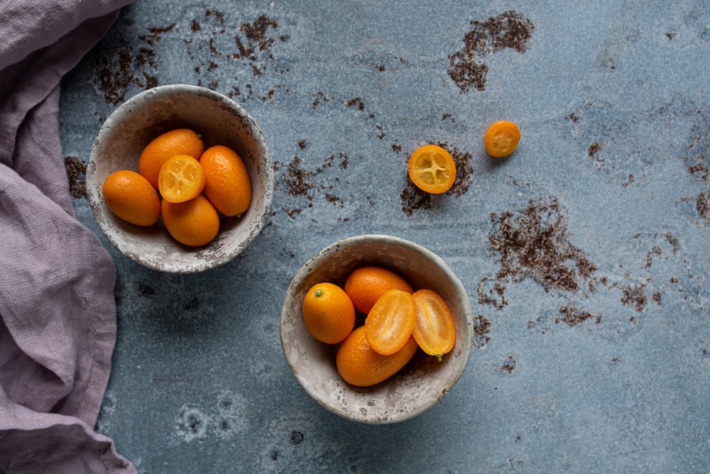a couple of bowls filled with oranges on top of a table
