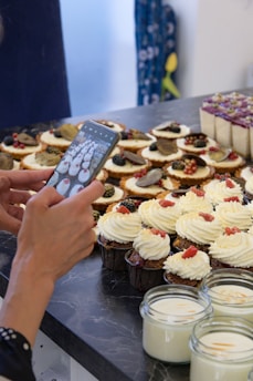 A cheerful confectioner taking photos of her elegant sweets setup for Instagram