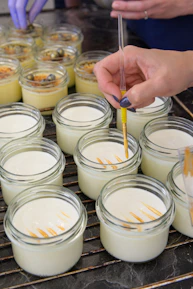 A smiling baker carefully layering ingredients into dessert jars in a cozy kitchen.