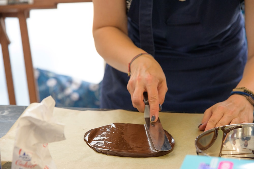 a woman is decorating a piece of chocolate