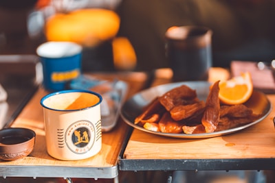 Branded coffee mugs and water bottles arranged on a wooden table with natural light.