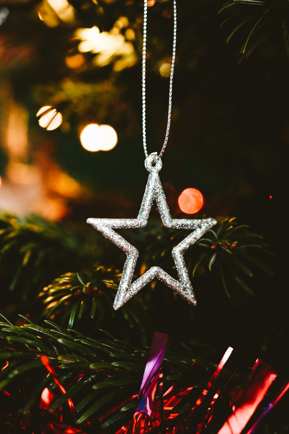 a silver star ornament hanging from a christmas tree