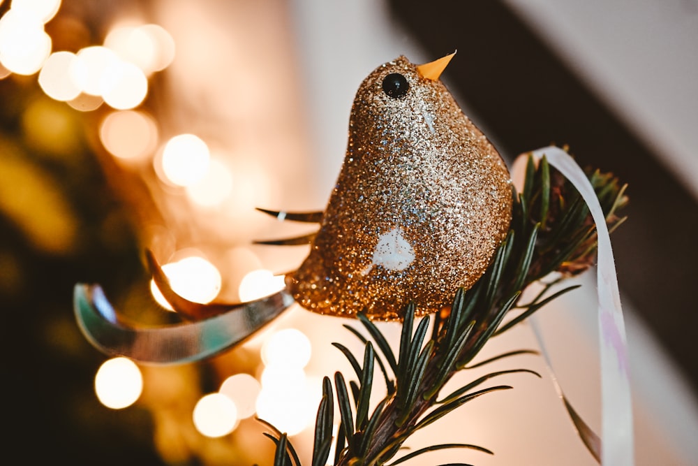 a gold bird ornament hanging from a pine tree