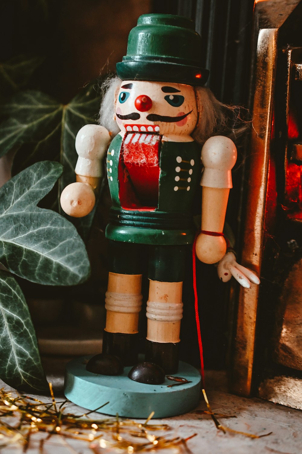 a wooden nutcracker standing next to a plant