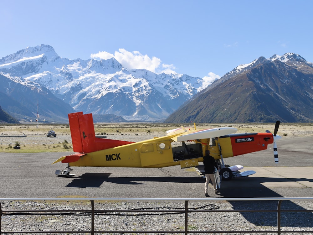 a small yellow and red plane on a runway
