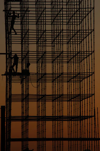 a man working on a scaffold at sunset