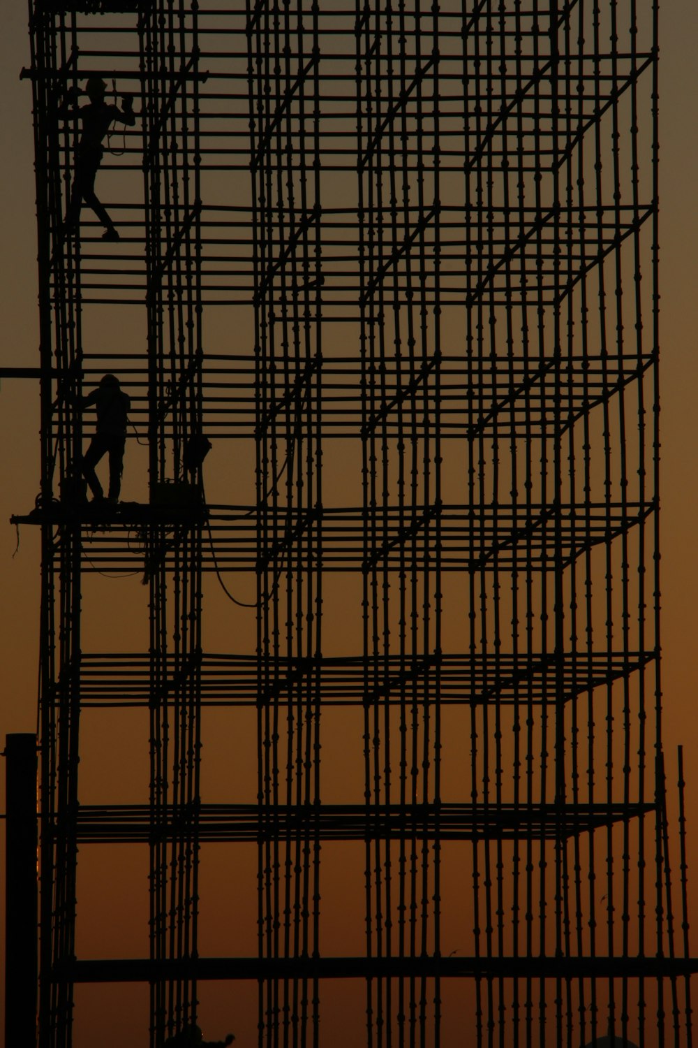 a man working on a scaffold at sunset
