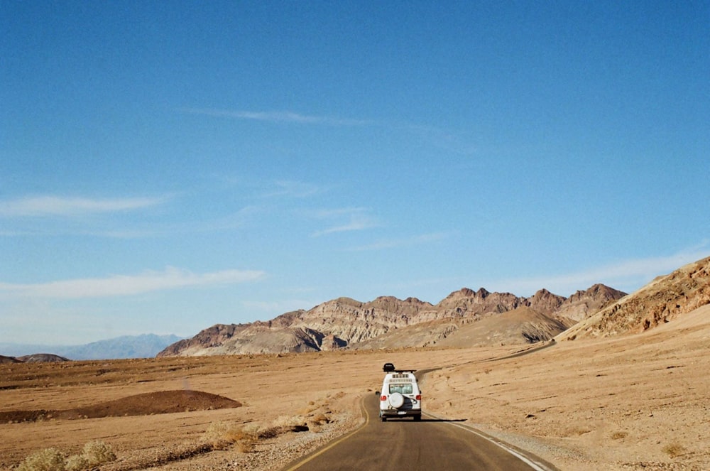 a white truck driving down a desert road