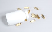 A detailed shot of supplement capsules spilling out of a transparent bottle.