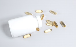 A detailed shot of supplement capsules spilling out of a transparent bottle.