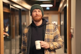 a man with a beard holding a cup of coffee