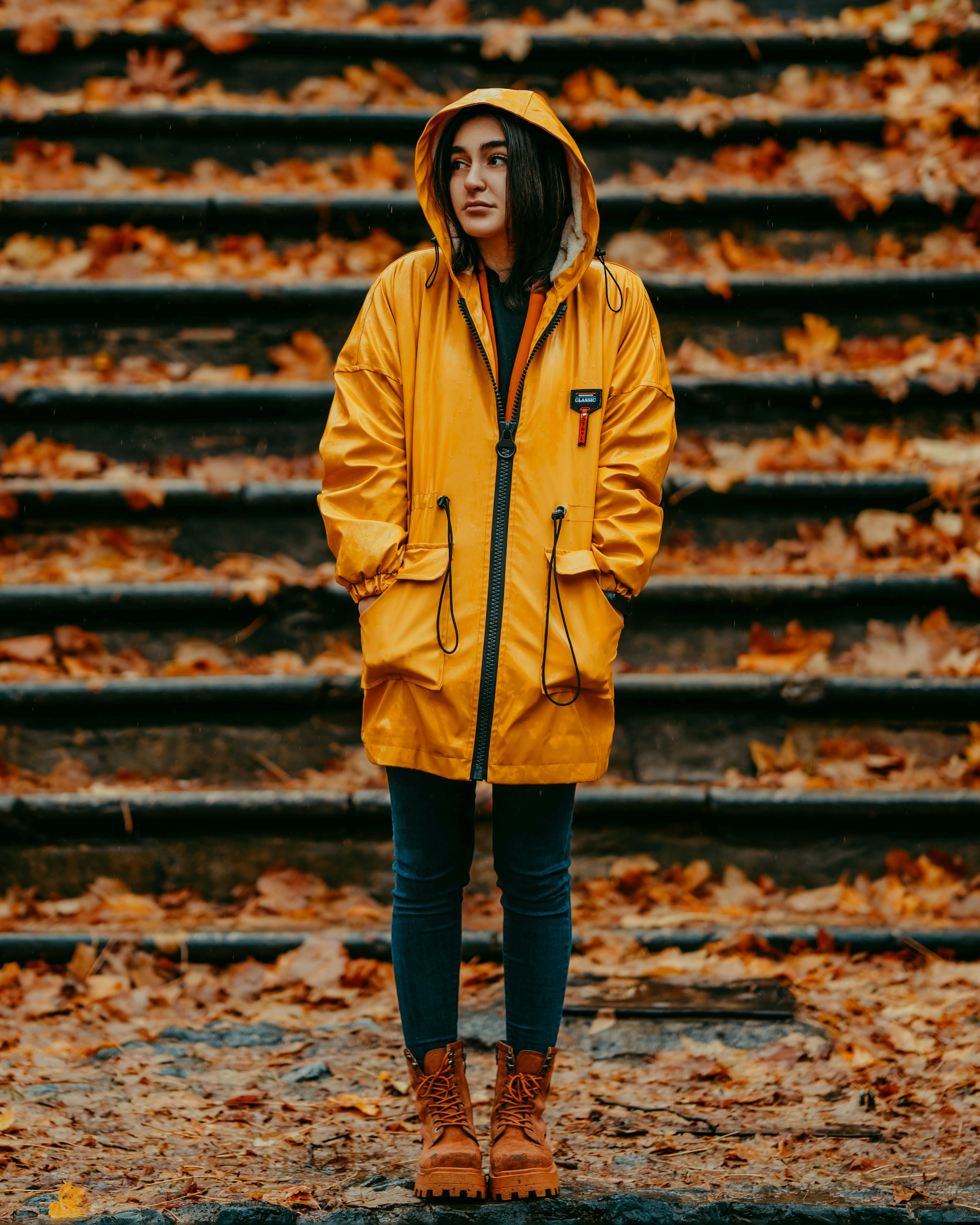 A woman in a yellow raincoat standing in front of stairs photo – Free ...