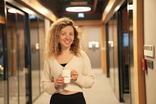 a woman holding a cup of coffee in a hallway