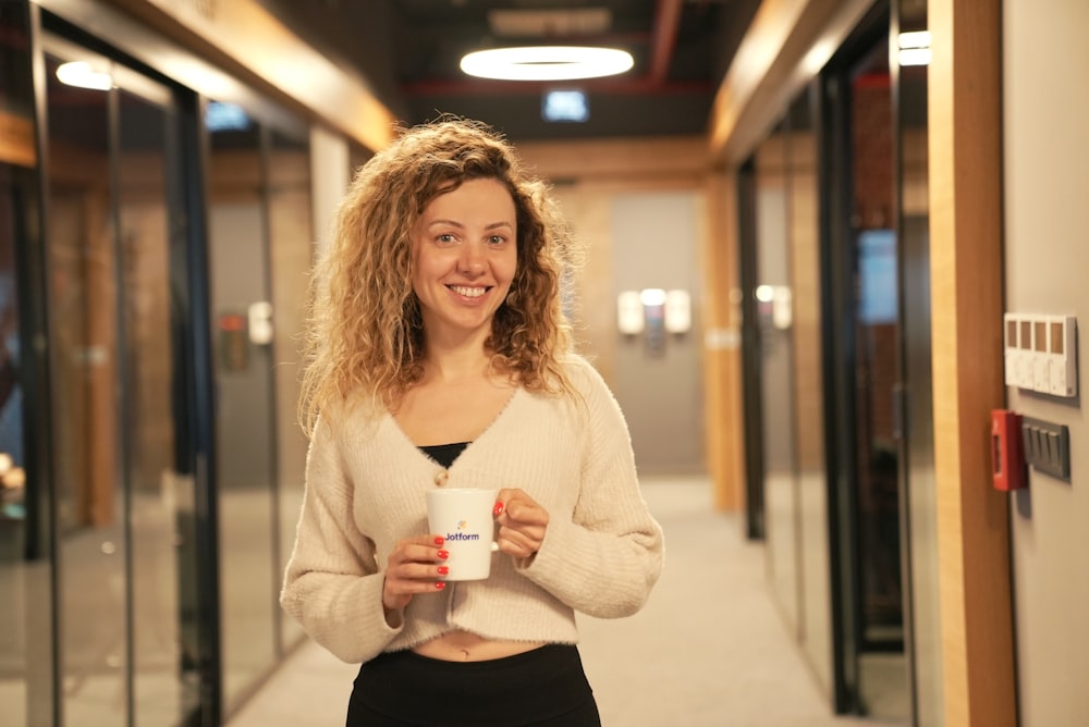 a woman holding a cup of coffee in a hallway