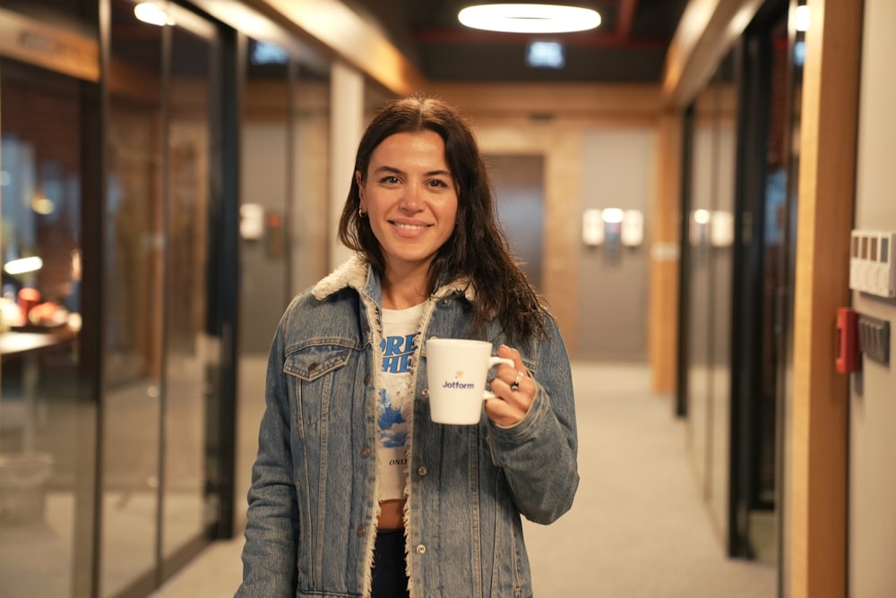 a woman holding a cup of coffee in a hallway