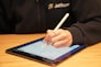 a person writing on a tablet with a pen