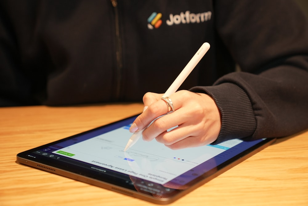 a person writing on a tablet with a pen