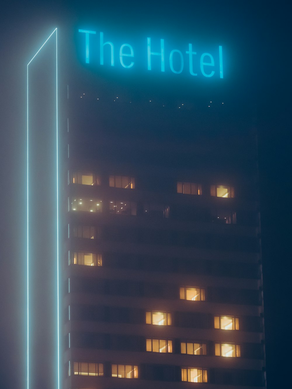 a tall building with a neon sign on top of it