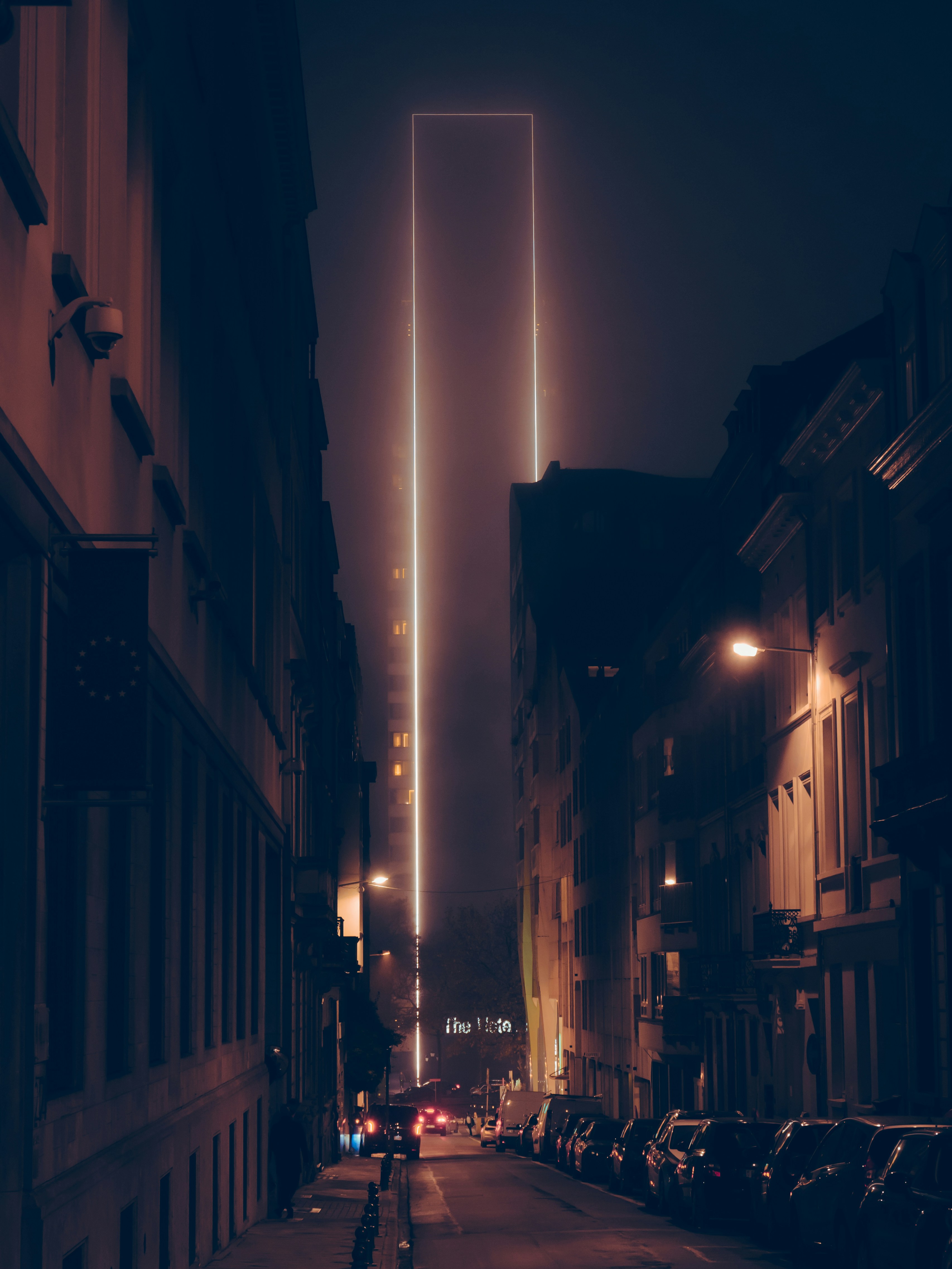 a city street at night with cars parked on the side of the street
