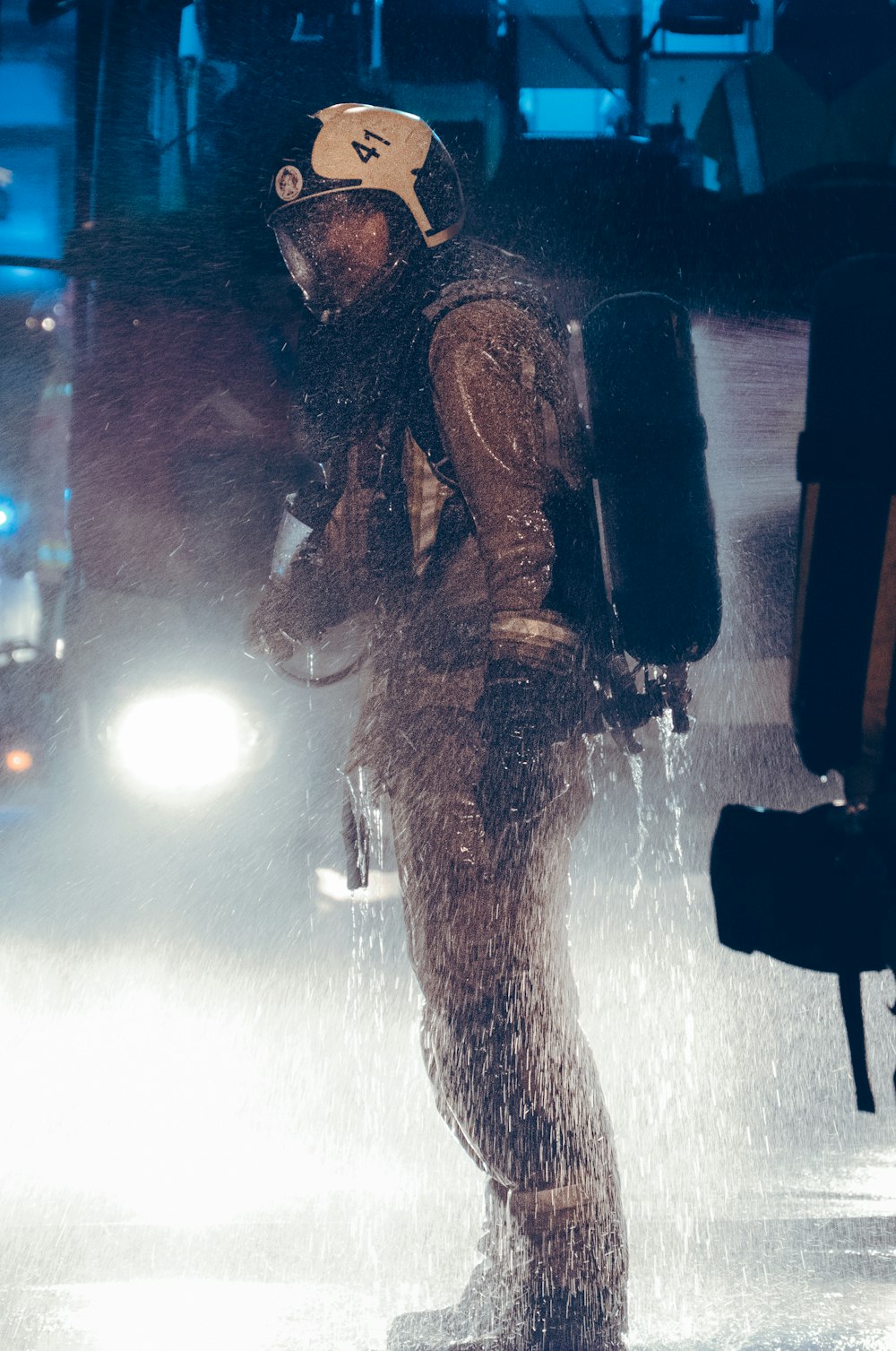 a man in a wet suit and helmet standing in the rain