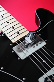a black electric guitar with a red background