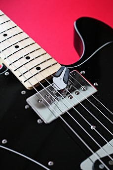 a black electric guitar with a red background