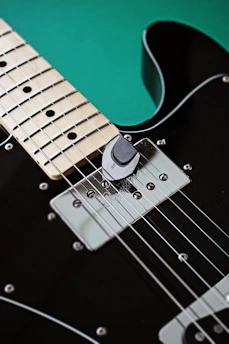 a black electric guitar with a green background