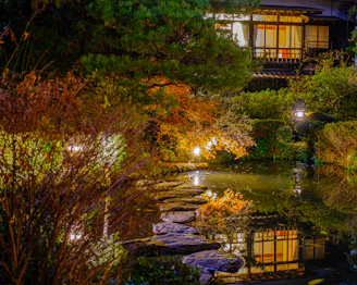 A peaceful temple garden in Kyoto illuminated by soft evening lights under a starry sky.