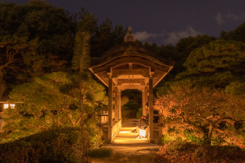 a person sitting on a bench under a gazebo at night