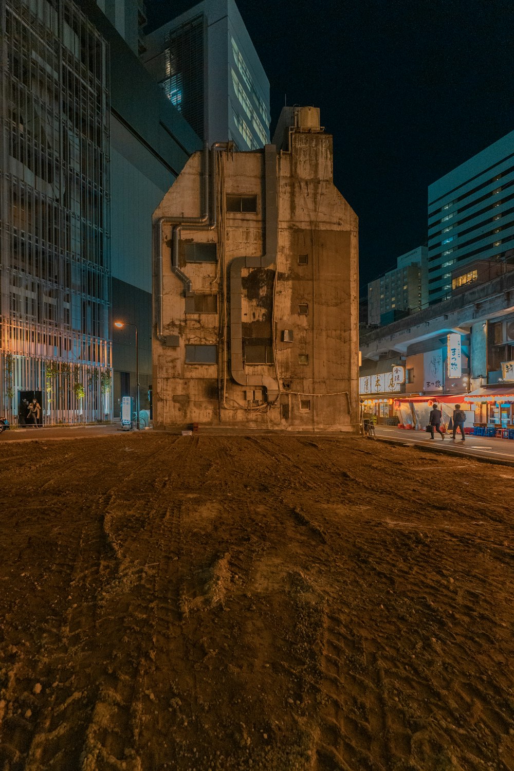 a very tall building sitting in the middle of a dirt field