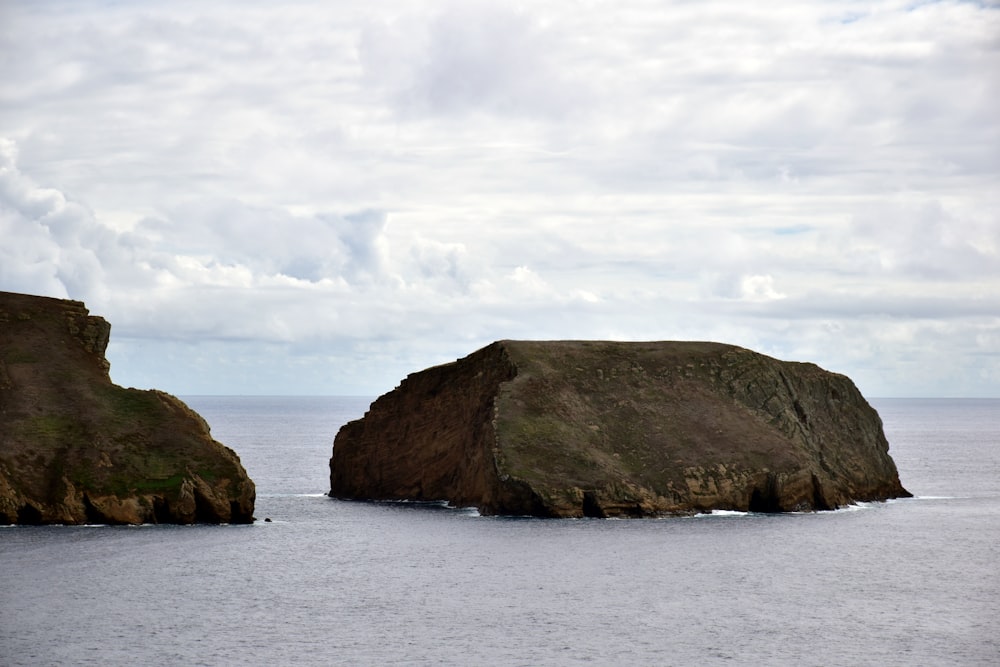 a couple of large rocks sitting in the middle of the ocean