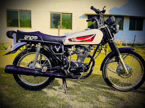 A vintage motorcycle with chrome details parked in front of an American flag backdrop.