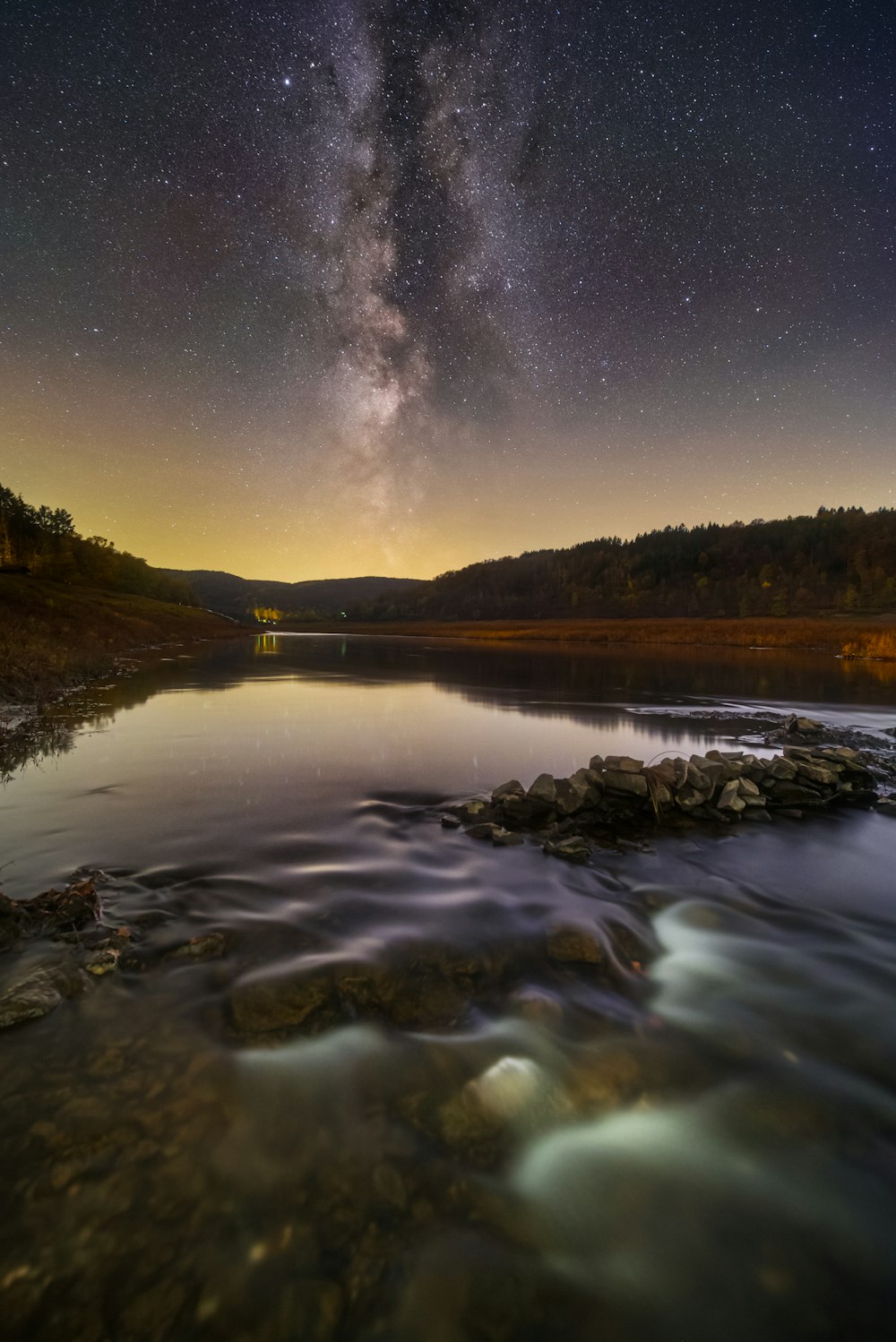 the night sky is filled with stars above a body of water